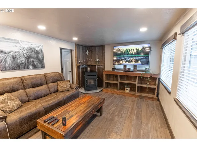 a living room with furniture a large window and wooden floor