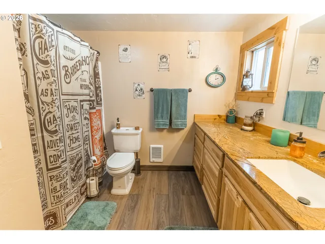 a bathroom with a granite countertop sink toilet and shower curtains