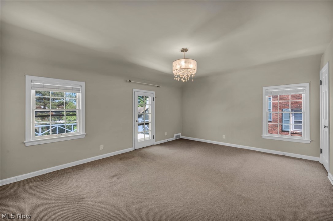3543 Lytle Road Shaker Heights, OH 44122 - Photo 32 of 49 Neutral-toned room featuring a decorative chandelier, two windows with white trim, and a glass-paneled door