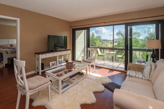 a living room with furniture a flat screen tv and a floor to ceiling window