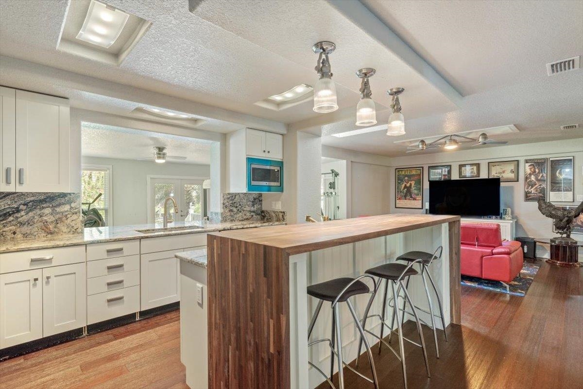 6342 Salado Road St. Augustine, FL 32080 - Photo 22 of 74 a kitchen with stainless steel appliances kitchen island granite countertop a table chairs in it and wooden floors