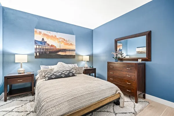 a bedroom with a bed and a lamp on dresser