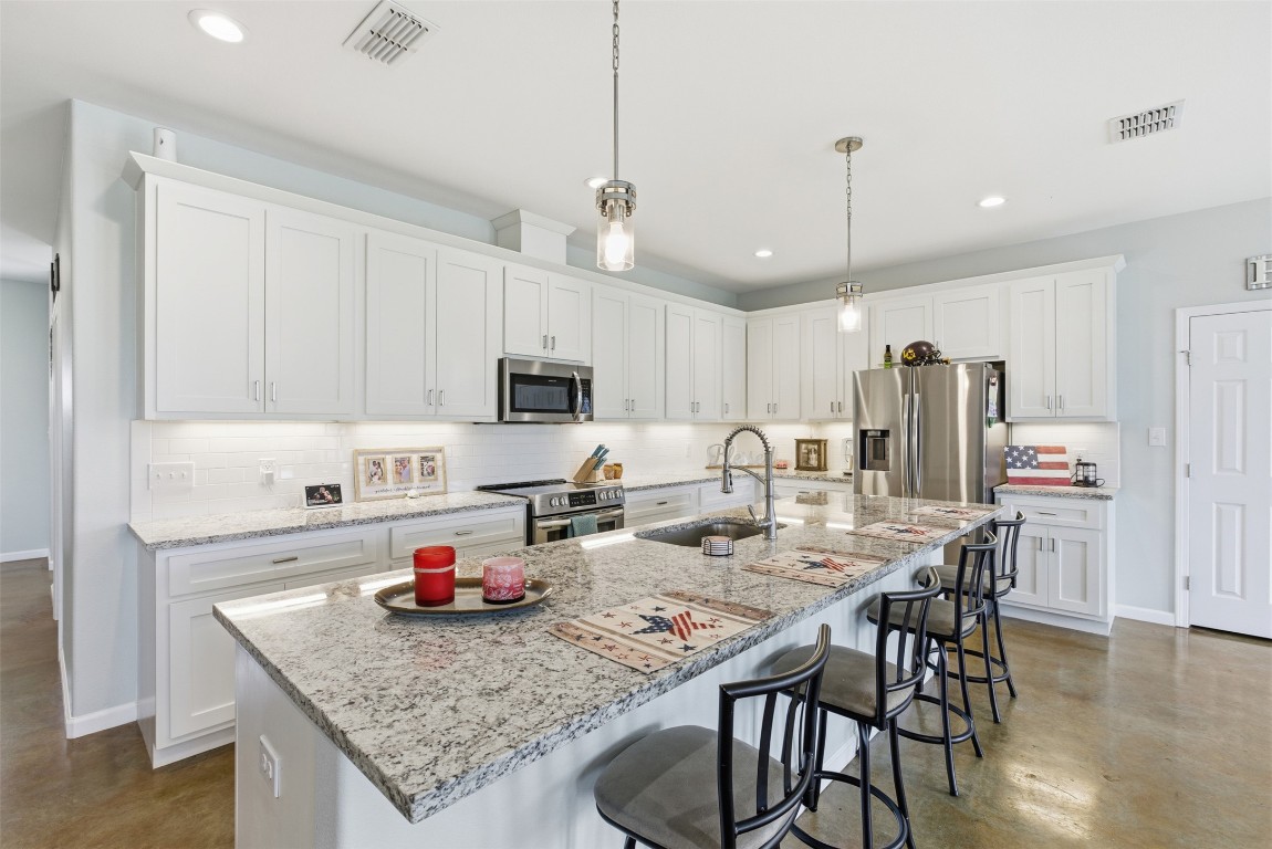 152 Spring Hollow Trail Smithville, TX 78957 - Photo 17 of 17 a kitchen with stainless steel appliances granite countertop a kitchen island a stove a table and chairs