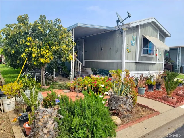a front view of a house with lots of flower and a yard