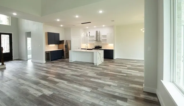 a view of kitchen with kitchen island granite countertop refrigerator and sink