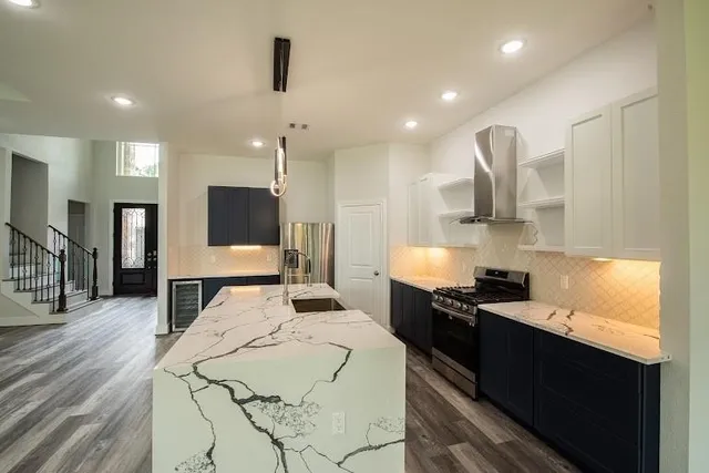 a kitchen with stainless steel appliances kitchen island granite countertop a sink a stove and cabinets