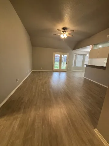 a view of empty room with wooden floor and fan