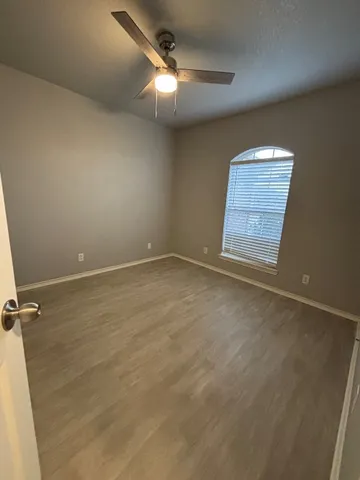 an empty room with windows and fan