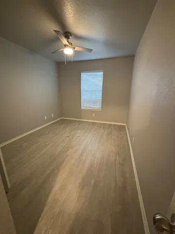 an empty room with a wooden floor and a ceiling fan