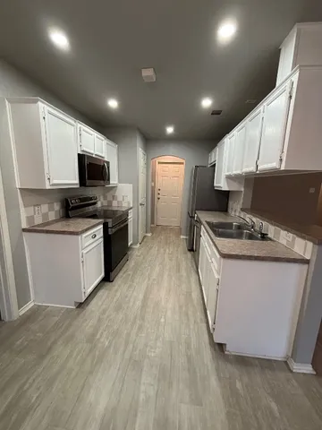 a large kitchen with stainless steel appliances granite countertop a stove a sink dishwasher and a microwave with wooden floor