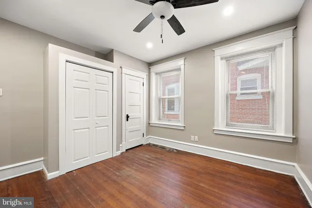 an empty room with wooden floor chandelier and windows