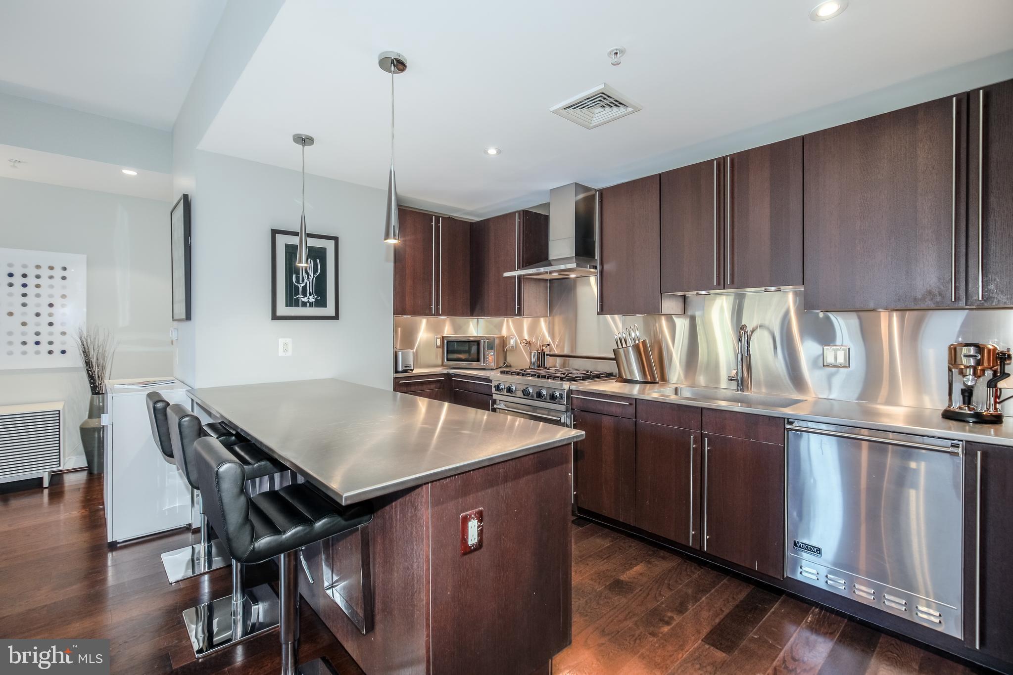 2425 L Street Northwest, Unit 211 Washington, DC 20037 - Photo 7 of 43 a kitchen with kitchen island granite countertop a sink counter and chairs