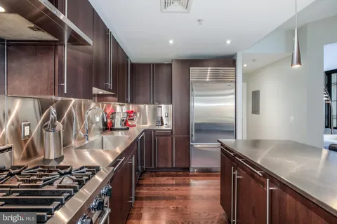 a kitchen with kitchen island stainless steel appliances a sink stove and refrigerator