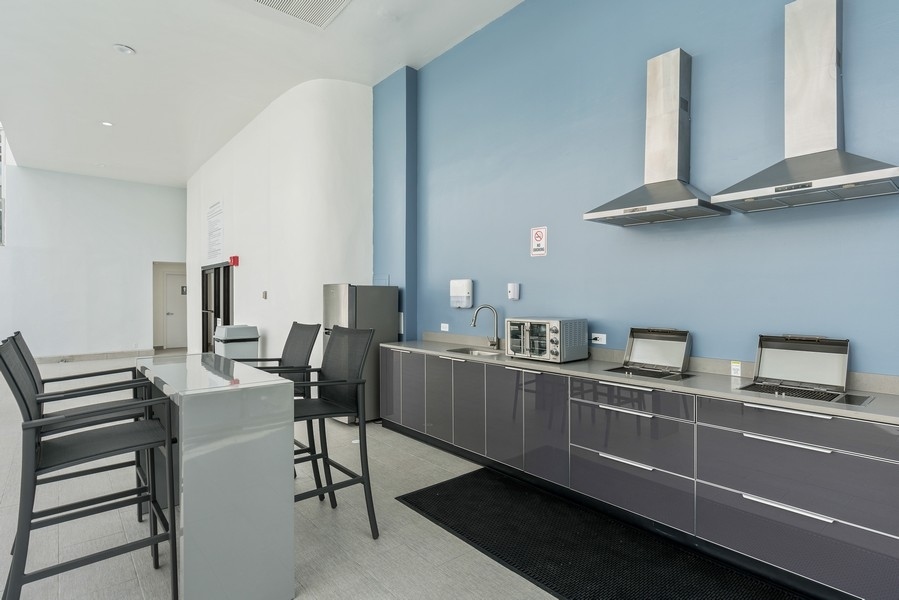 1221 North Dearborn Parkway, Unit PH10N Chicago, IL 60610 - Photo 19 of 23 a kitchen with stainless steel appliances kitchen island granite countertop a sink cabinets and wooden floor