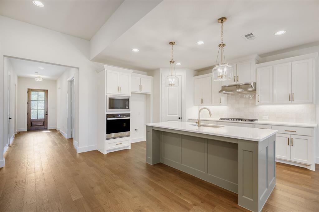 4314 Haley Way Oak Point, TX 75068 - Photo 8 of 28 Kitchen featuring a central island with a contrasting base, white countertops, and a built-in sink