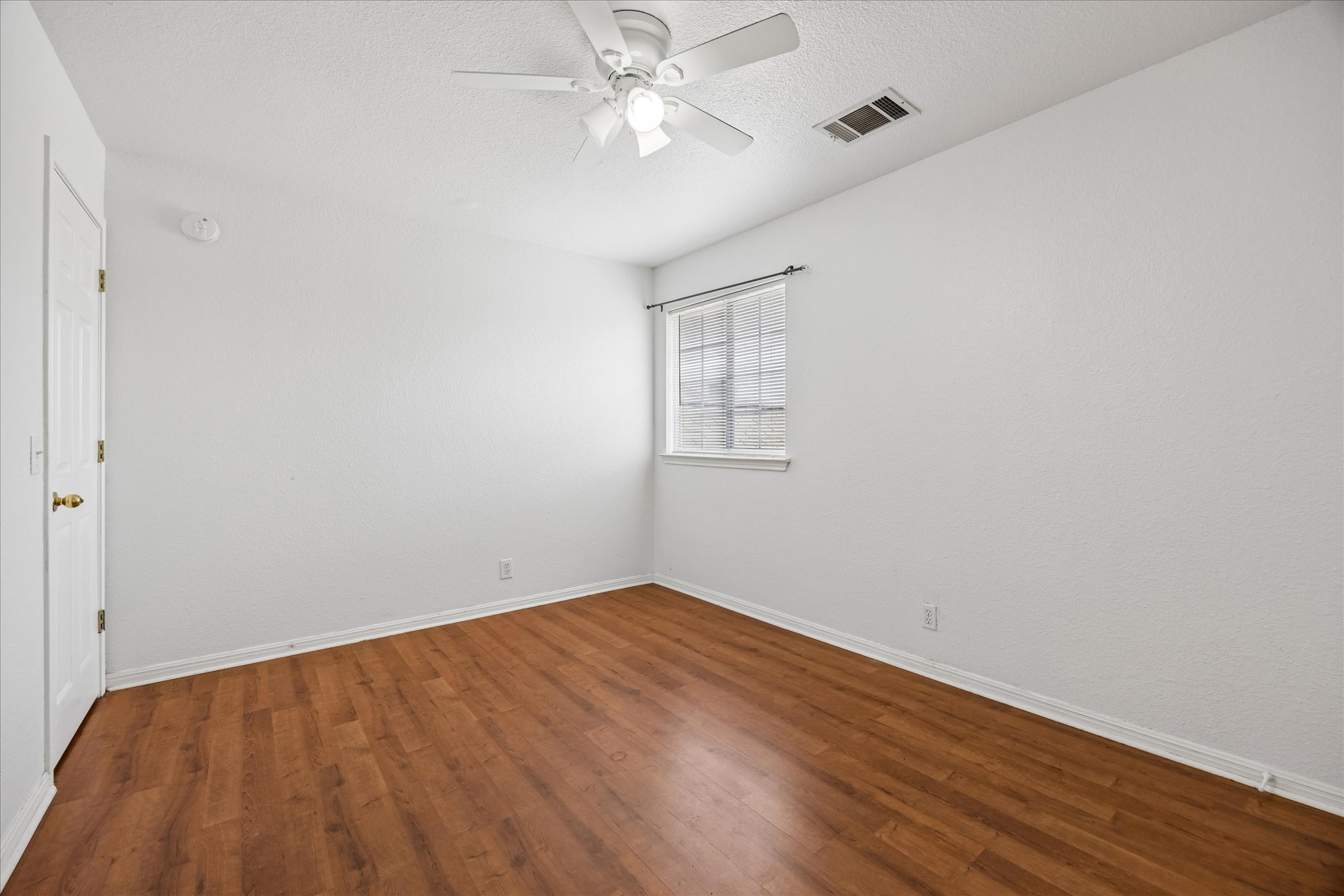 124 Lago Grande Drive Kyle, TX 78640 - Photo 11 of 16 Room featuring wood-finish flooring, a window with horizontal blinds, a ceiling fan, and white painted walls