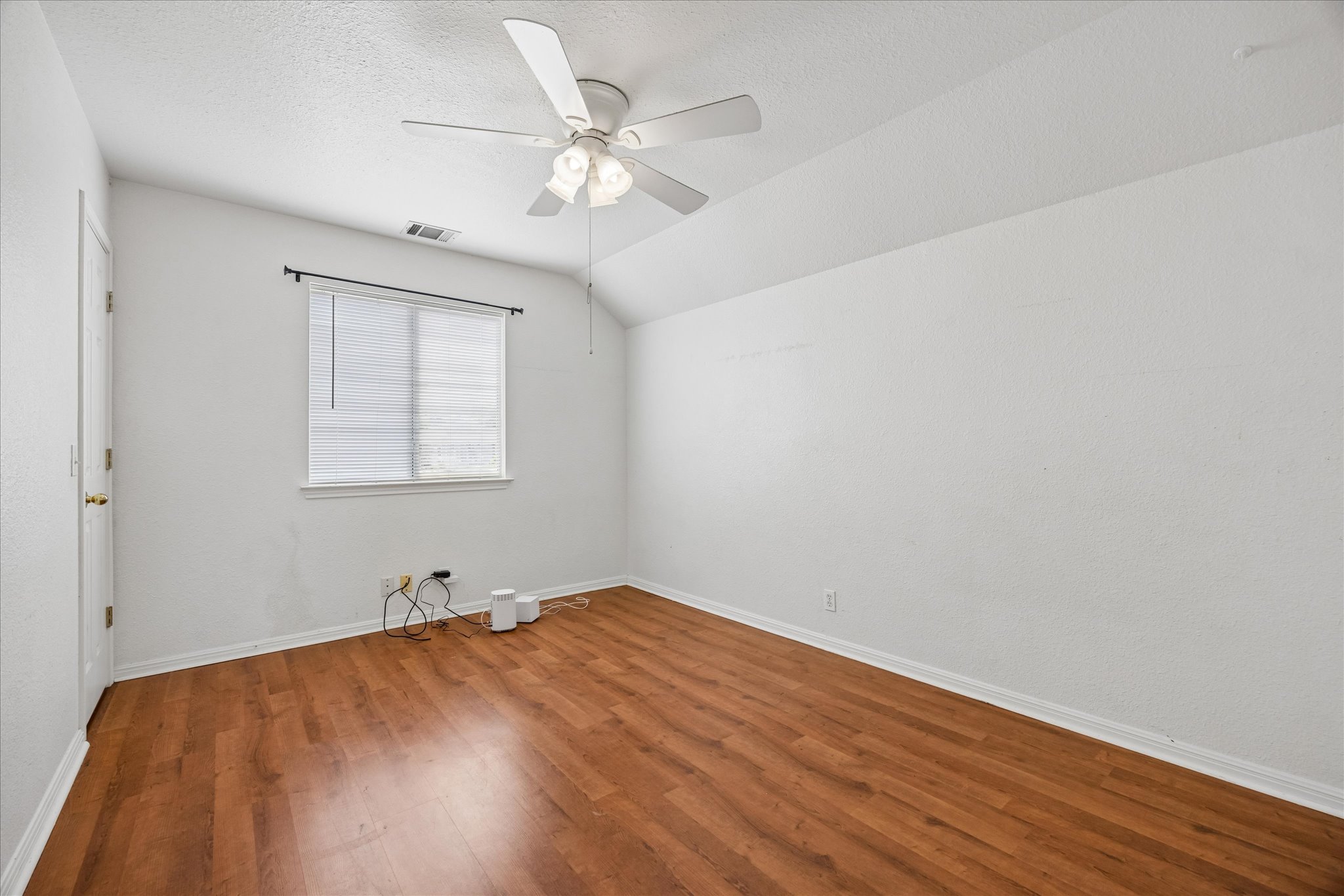 124 Lago Grande Drive Kyle, TX 78640 - Photo 12 of 16 Room featuring wood-finish flooring, white walls, and a sloped ceiling