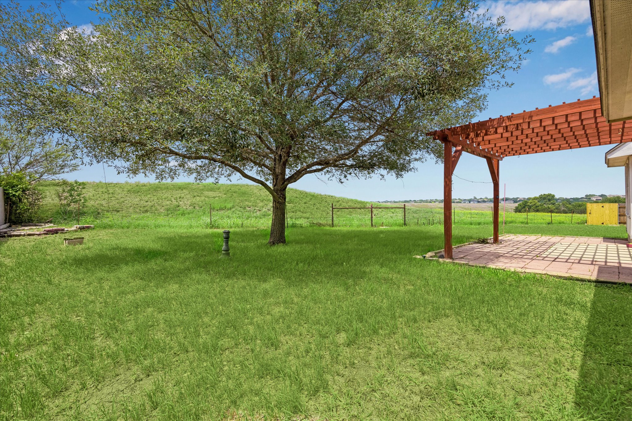 124 Lago Grande Drive Kyle, TX 78640 - Photo 15 of 16 Spacious backyard featuring a large tree, a wood pergola, and a stone paver patio