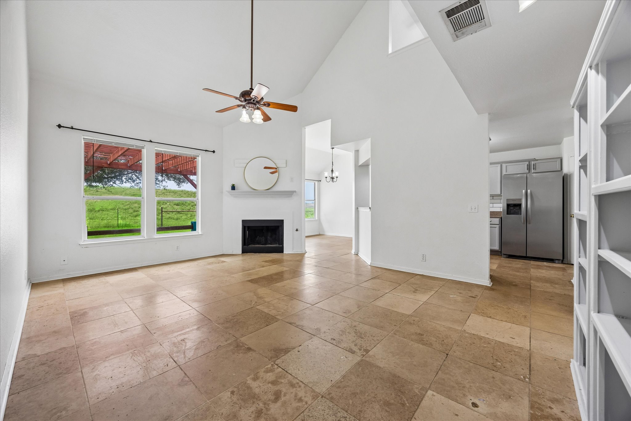 124 Lago Grande Drive Kyle, TX 78640 - Photo 2 of 16 Spacious living area featuring high vaulted ceilings, large rectangular tile flooring, a fireplace with a mantel, and built-in shelving