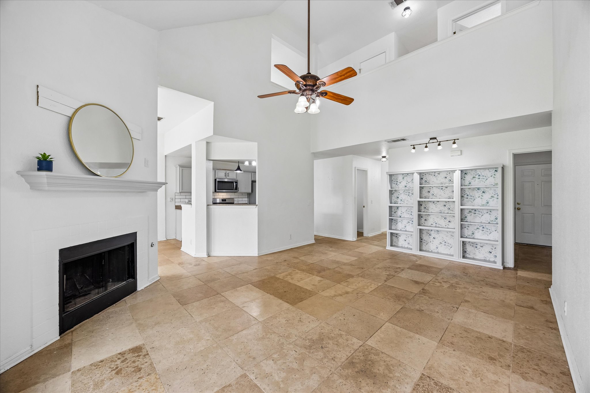 124 Lago Grande Drive Kyle, TX 78640 - Photo 3 of 16 Vaulted ceilings over the living area featuring a fireplace, a ceiling fan, and built-in shelving