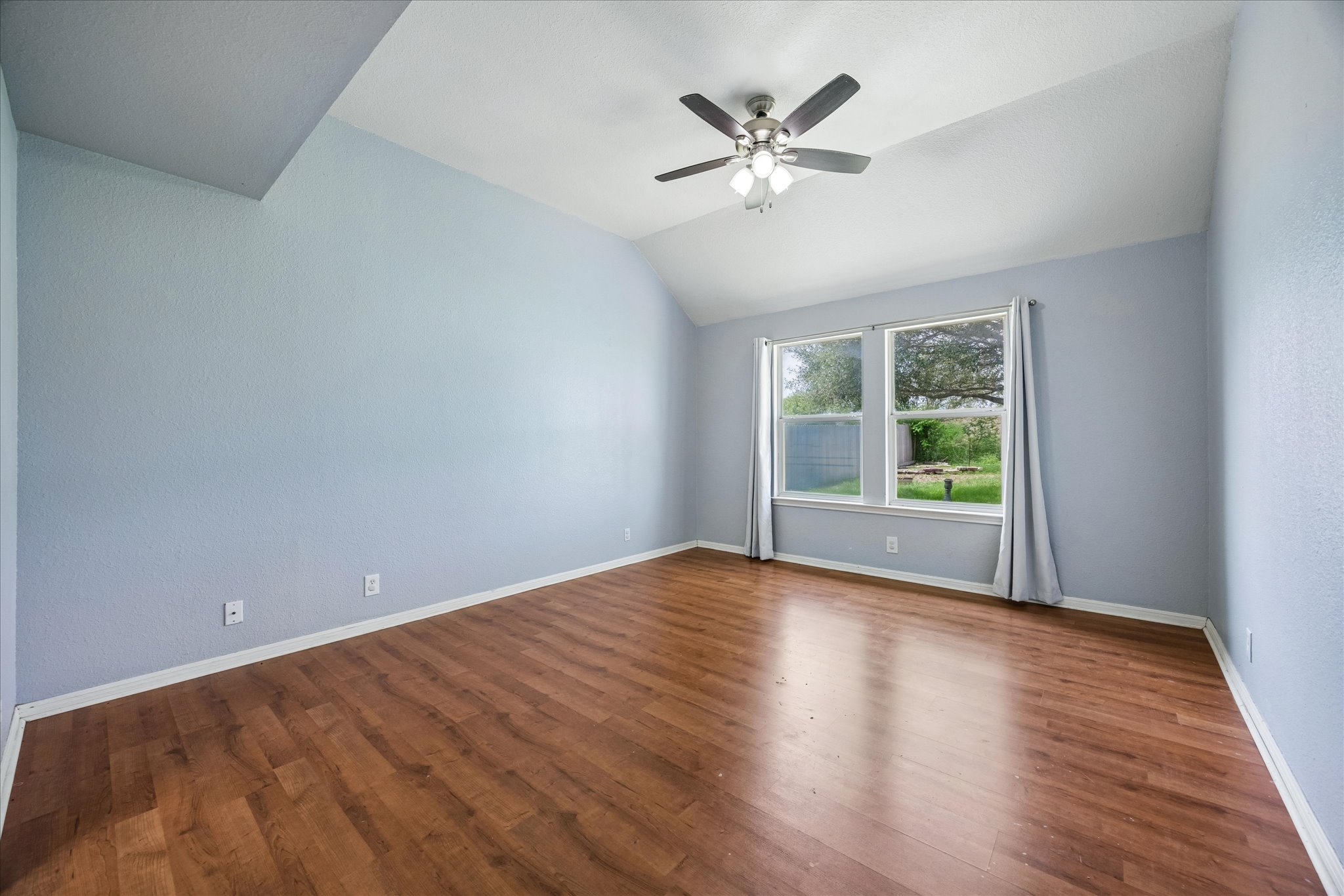 124 Lago Grande Drive Kyle, TX 78640 - Photo 7 of 16 Spacious room featuring vaulted ceilings, wood-finish flooring, and a contemporary ceiling fan