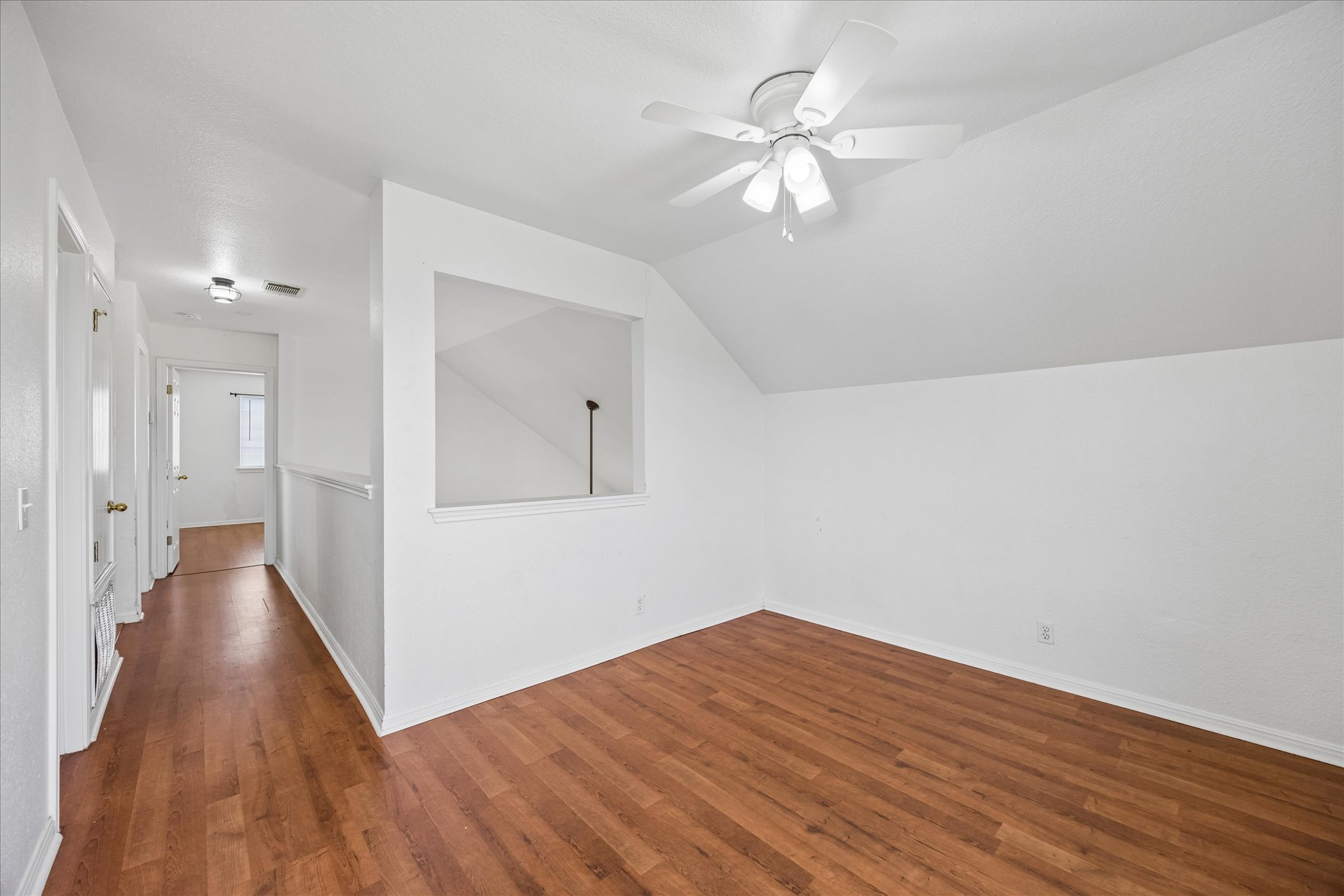 124 Lago Grande Drive Kyle, TX 78640 - Photo 9 of 16 Attic room featuring wood-finish flooring, an angled ceiling, a ceiling fan with integrated lighting, and a half-wall partition