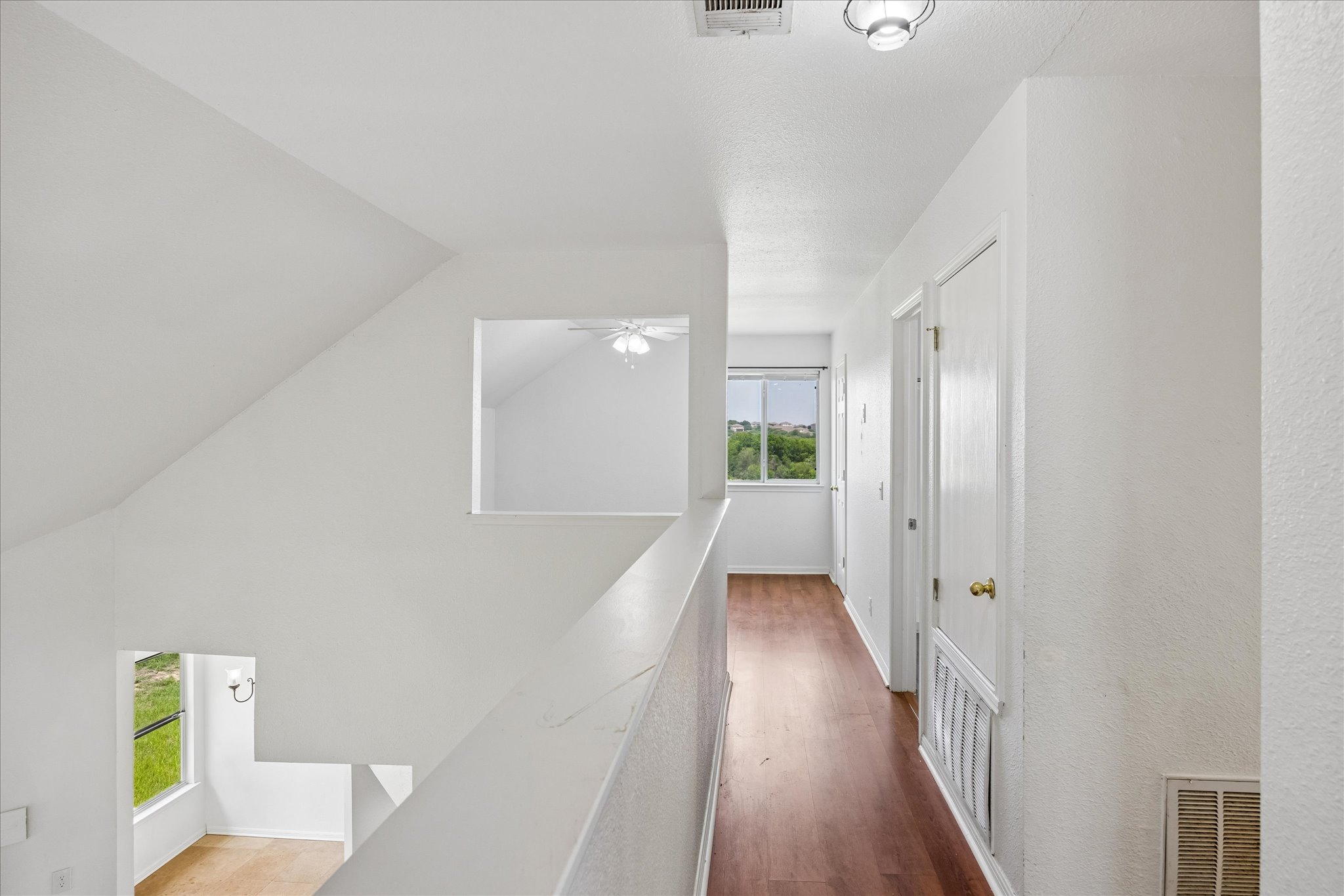 124 Lago Grande Drive Kyle, TX 78640 - Photo 10 of 16 Upper-level hallway featuring wood-finish flooring, white walls, and a window providing natural light