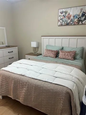 a bedroom with a bed and a lamp on dresser