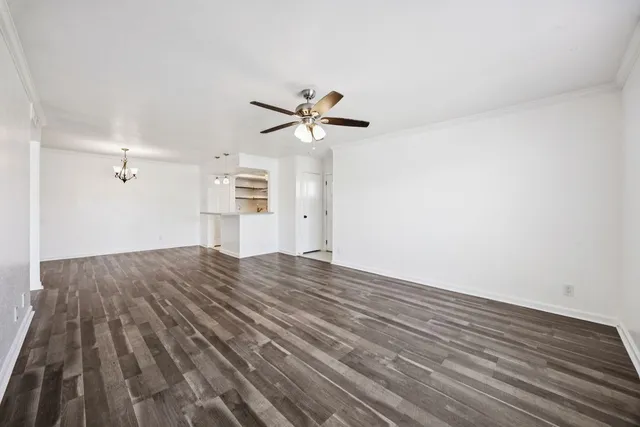 a view of empty room with wooden floor and kitchen