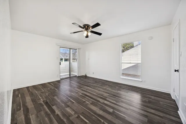 a view of empty room with wooden floor and ceiling fan