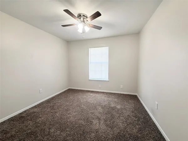 an empty room with a chandelier fan and windows