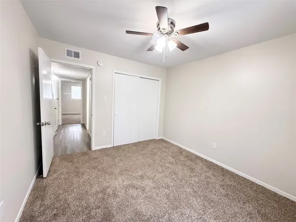 a view of an empty room and chandelier fan