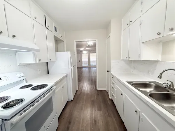 a kitchen with granite countertop a sink stove and cabinets