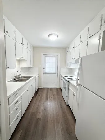 a kitchen with granite countertop a sink cabinets wooden floor and stainless steel appliances