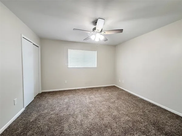 an empty room with a window and ceiling fan