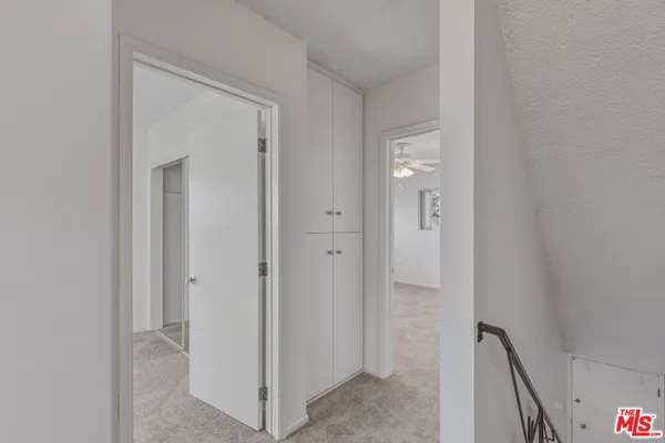 an empty room with a chandelier fan and closet
