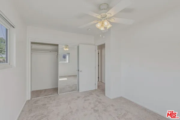 an empty room with a window and a fan