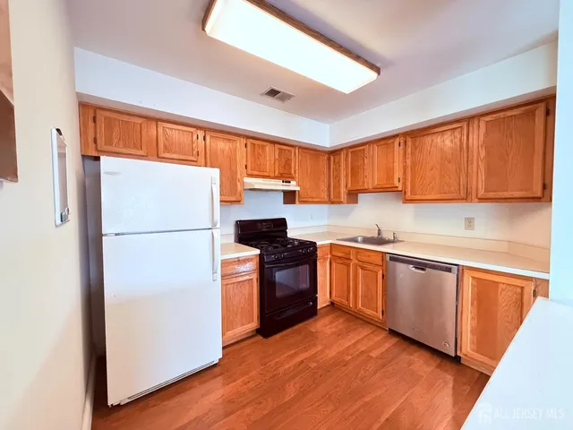 a kitchen with granite countertop wooden floors a stove a sink and a refrigerator