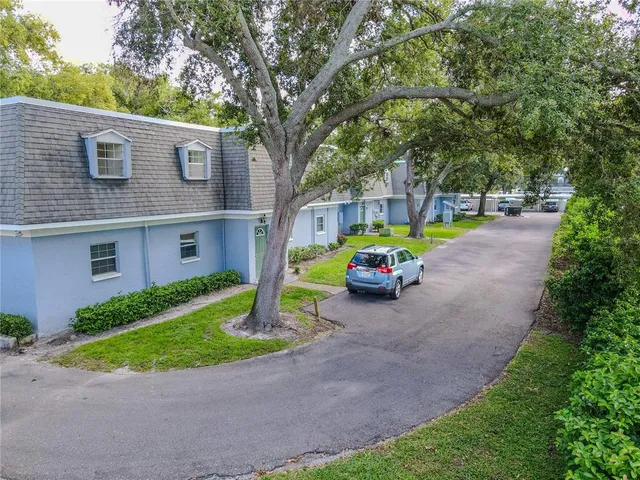 a view of a house with a small yard and a large tree