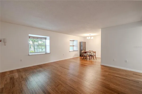 a view of empty room with wooden floor and a window