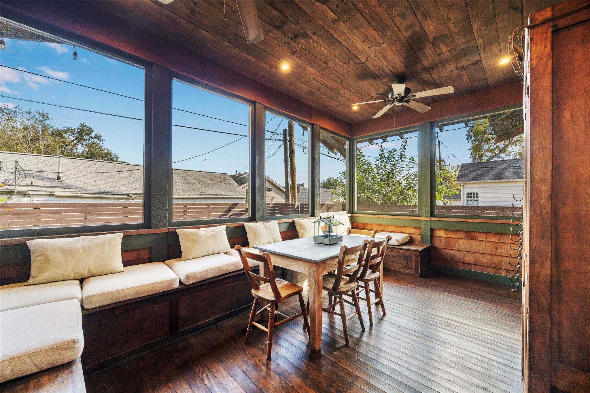 512 Archer Street Houston, TX 77009 - Photo 6 of 40 Incredible cedar-clad screened back porch featuring ceiling fans, hardwood floors, and built-in seating, all overlooking the backyard. Imagine the memories that will be made in this space!