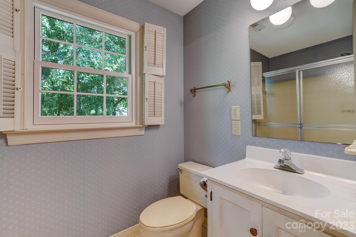10215 Hanover Glen Road Charlotte, NC 28210 - Photo 25 of 40 a bathroom with a granite countertop toilet a sink a mirror and a window
