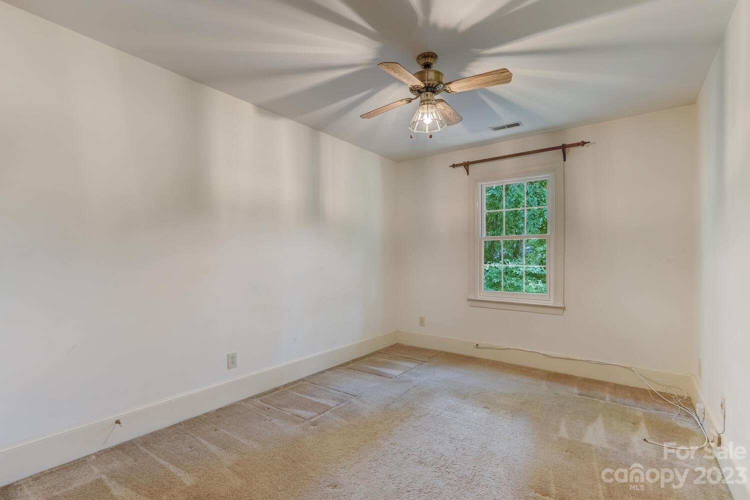 10215 Hanover Glen Road Charlotte, NC 28210 - Photo 31 of 40 an empty room with a chandelier fan and windows