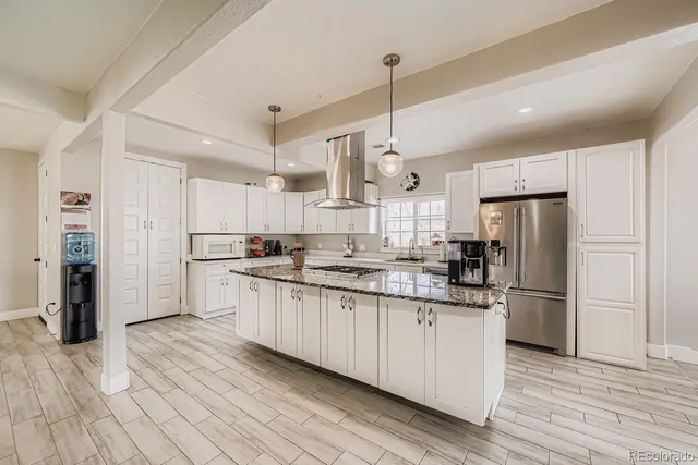 a kitchen with stainless steel appliances granite countertop a refrigerator a sink dishwasher a stove and white cabinets with wooden floor