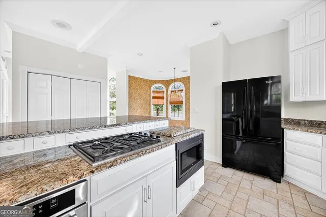 a kitchen with granite countertop a stove sink and refrigerator
