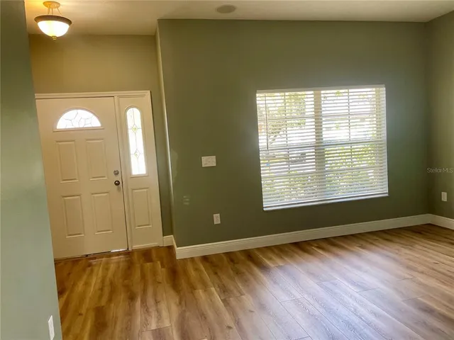 a view of an empty room with wooden floor and a window