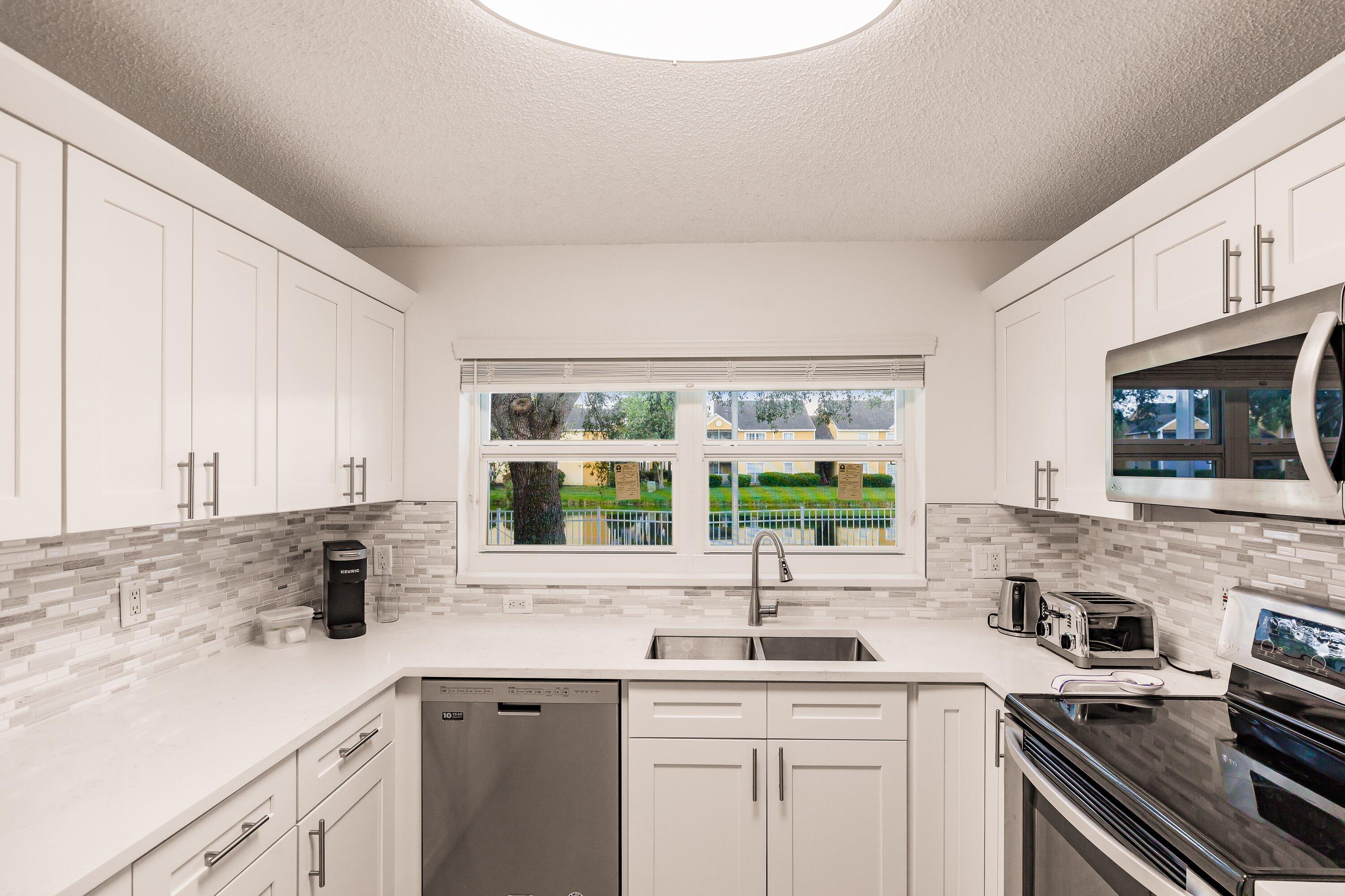 a kitchen with stainless steel appliances a sink a stove and white cabinets next to a window