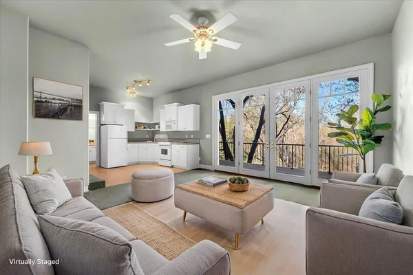 a living room with furniture and a large window with kitchen view