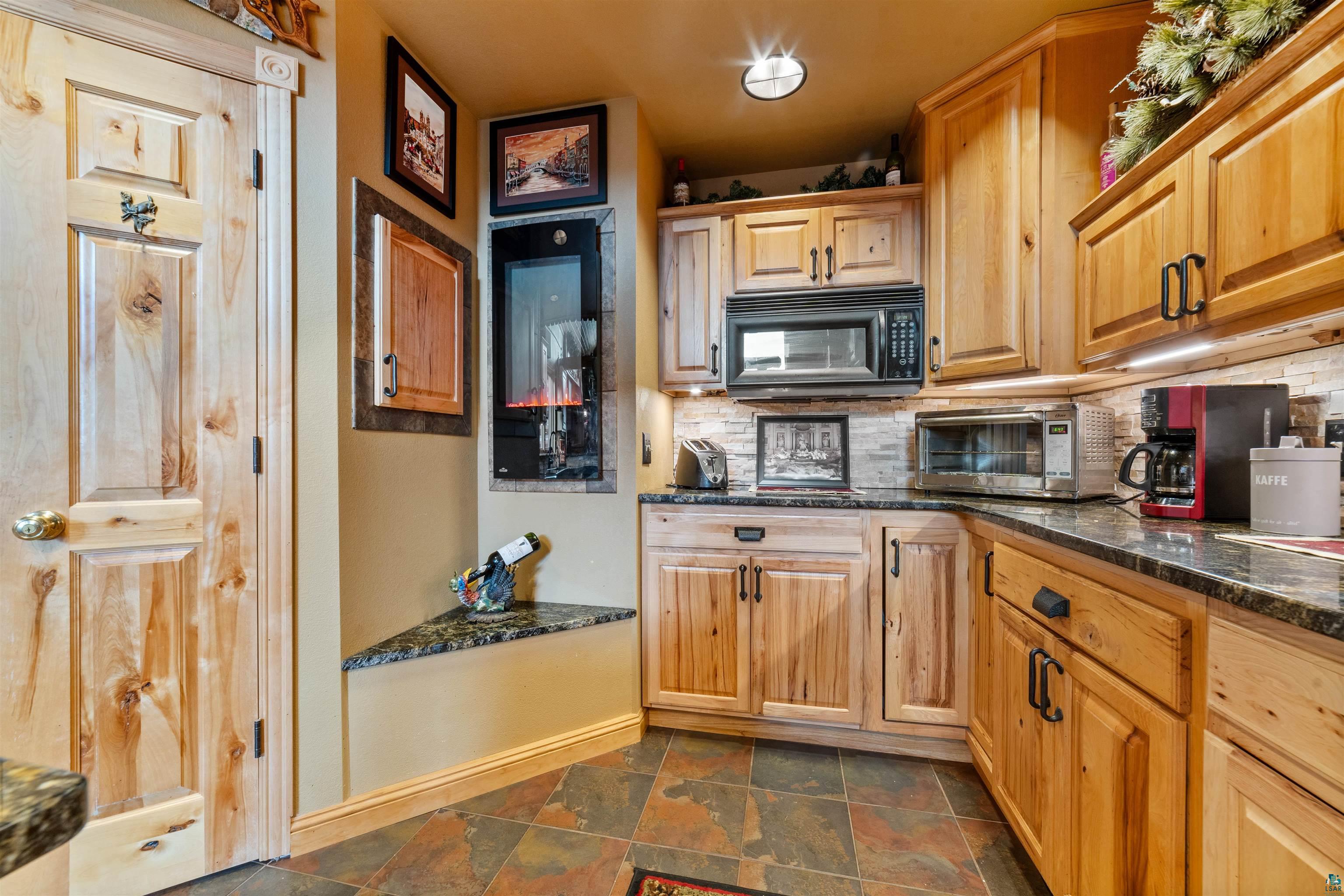 11911 East Rowe Road Lake Nebagamon, WI 54849 - Photo 12 of 61 Kitchen featuring light wood cabinetry, dark stone countertops, a microwave, and a beverage cooler