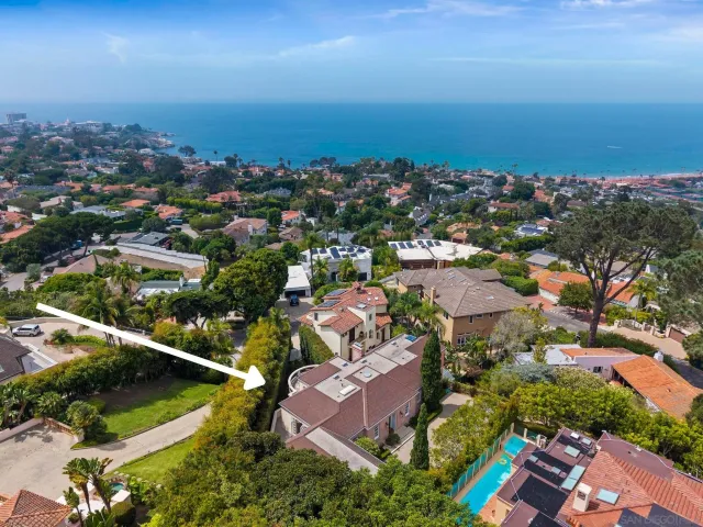 an aerial view of residential houses with outdoor space and ocean view